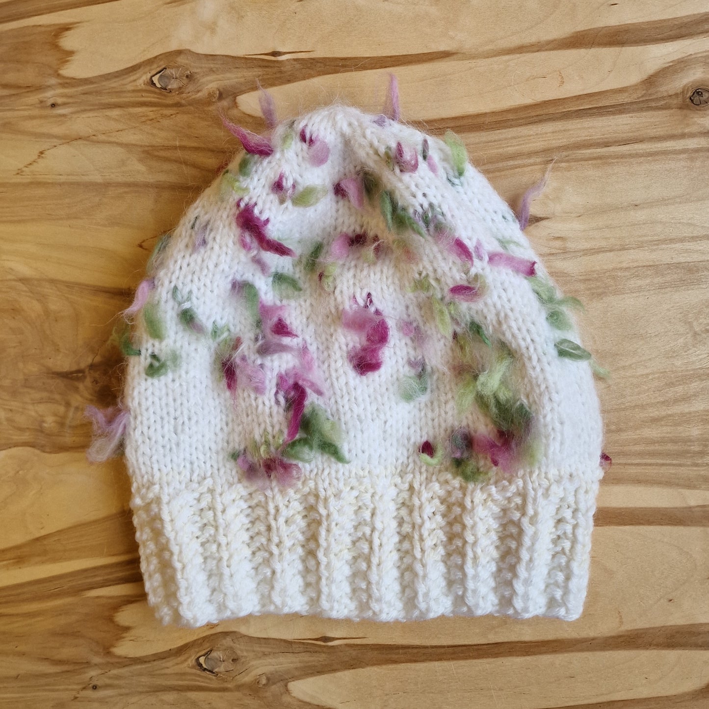 Rokām adīta balta cepure ar zaļiem un rozā elementiem (DZTO 68) - www.tiptip.lv