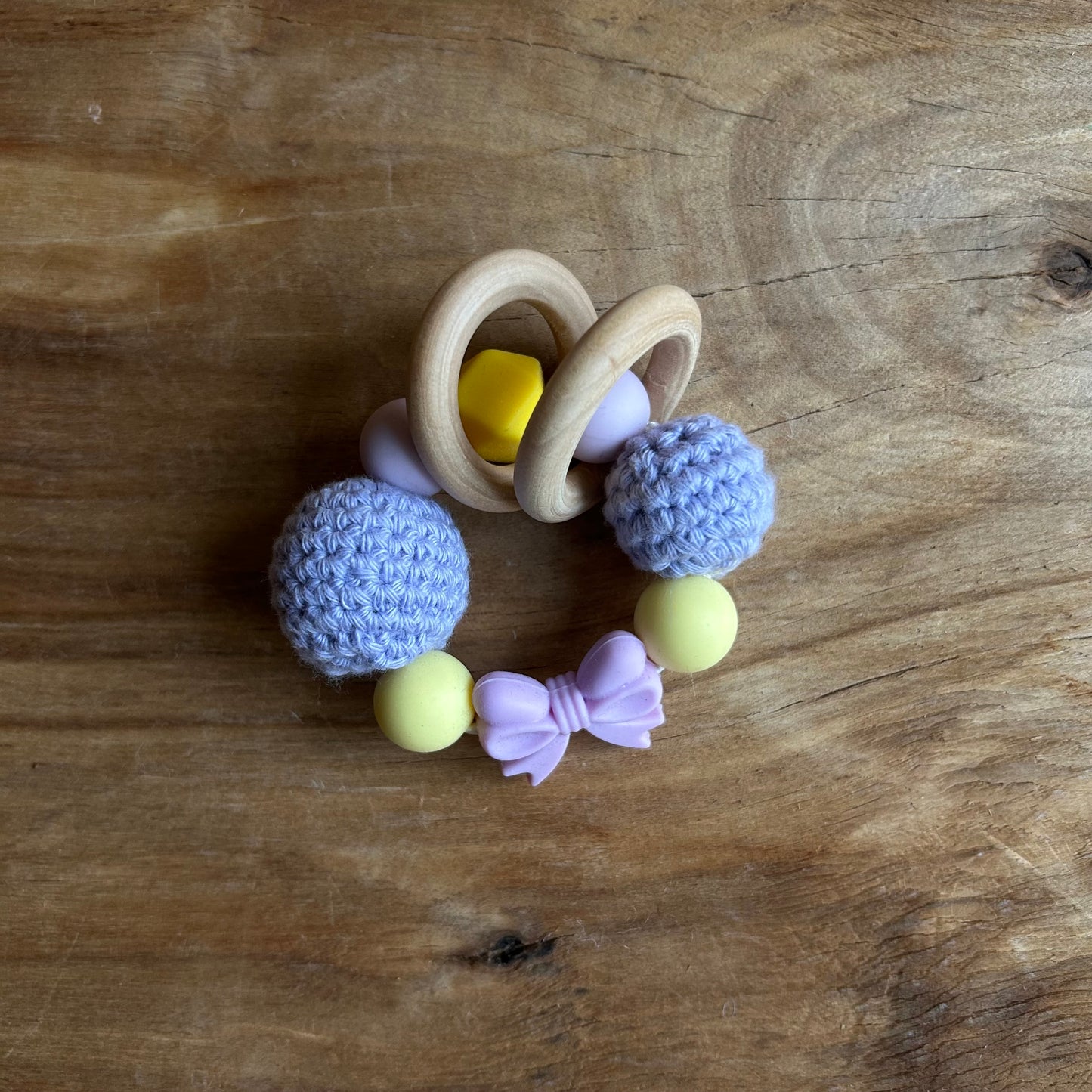 Tamborēts grabulītis lillā krāsā ar rozā silikona banti (AIPU 140)