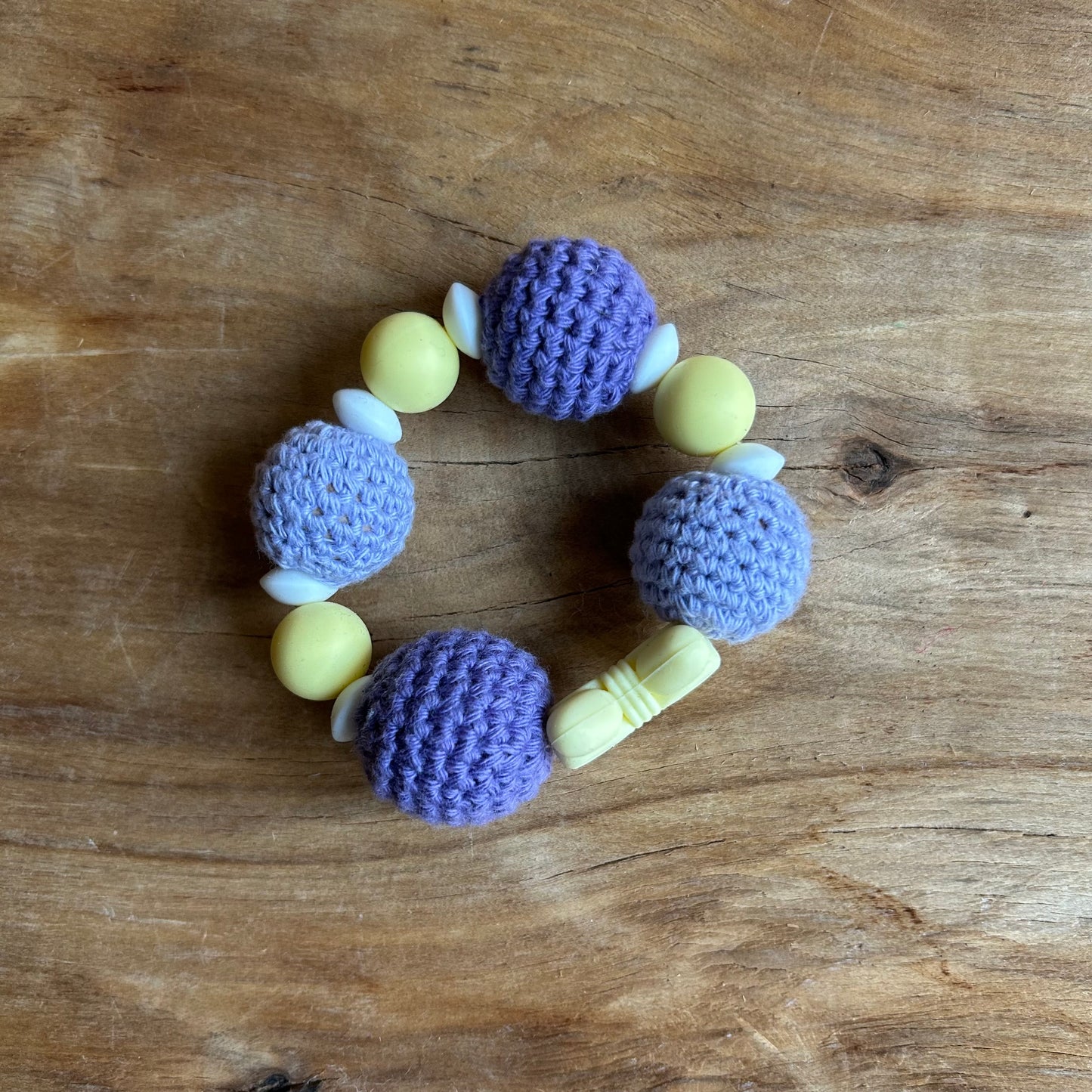 Tamborēts grabulītis lillā krāsā ar dzeltenu silikona pušķi (AIPU 138)