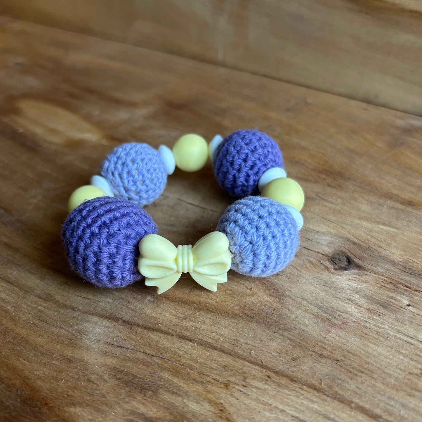 Tamborēts grabulītis lillā krāsā ar dzeltenu silikona pušķi (AIPU 138)