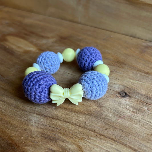 Tamborēts grabulītis lillā krāsā ar dzeltenu silikona pušķi (AIPU 138)