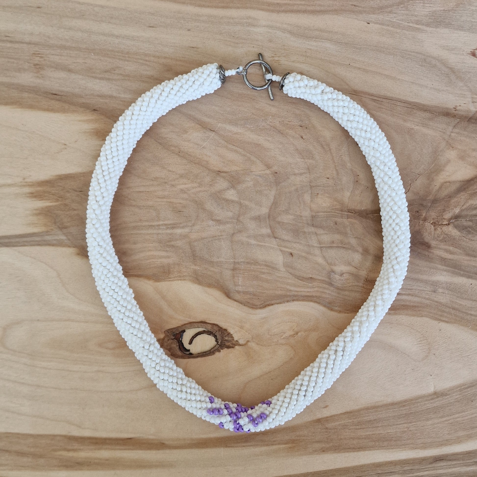 Balta tuneļtehnikas sīkpērlīšu kaklarota ar violetu akcentu (DAMI 21) - www.tiptip.lv 