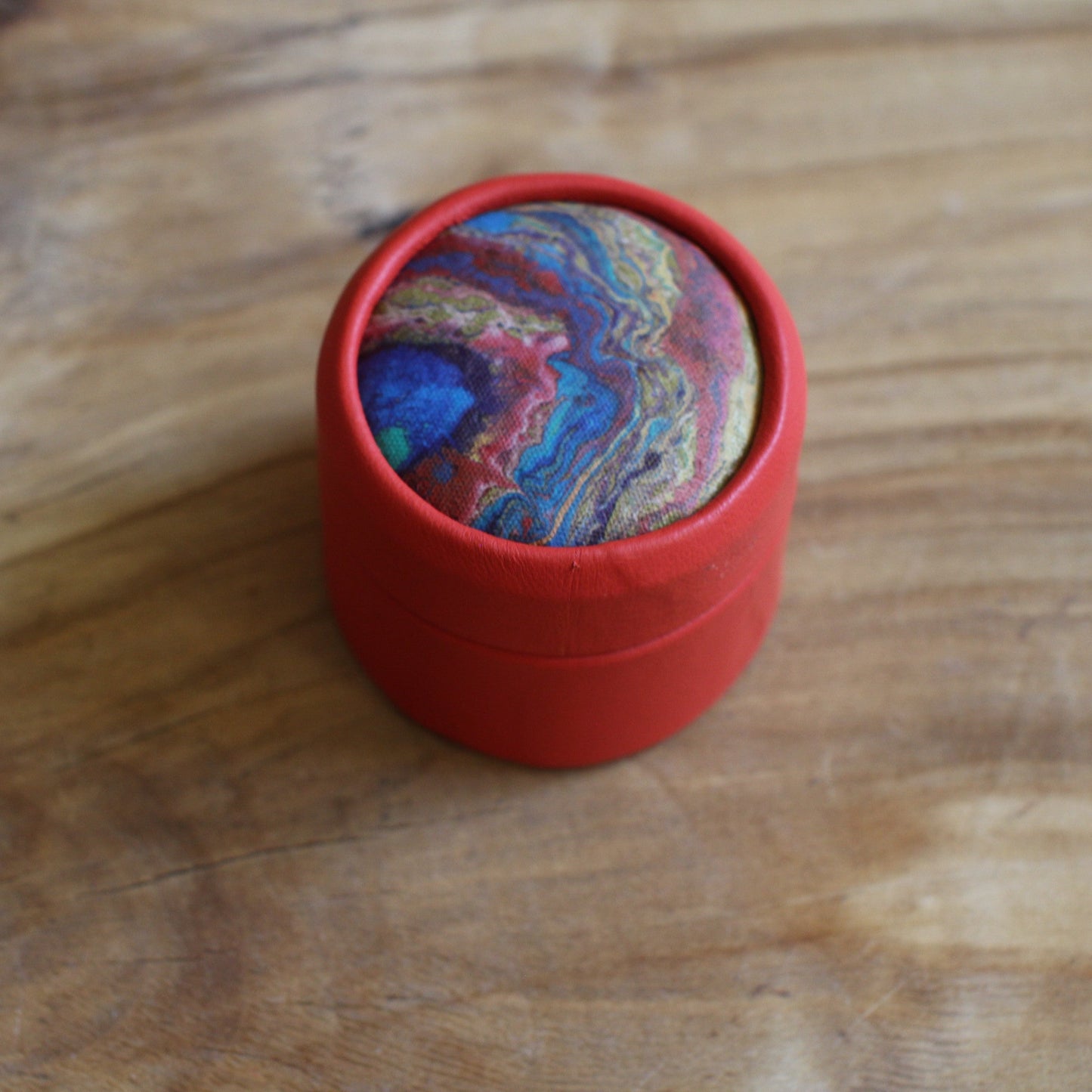 Sarkana, apaļa dekoratīva ādas kārbiņa (S) ar zilgani marmorētu vāku (RARA 252)