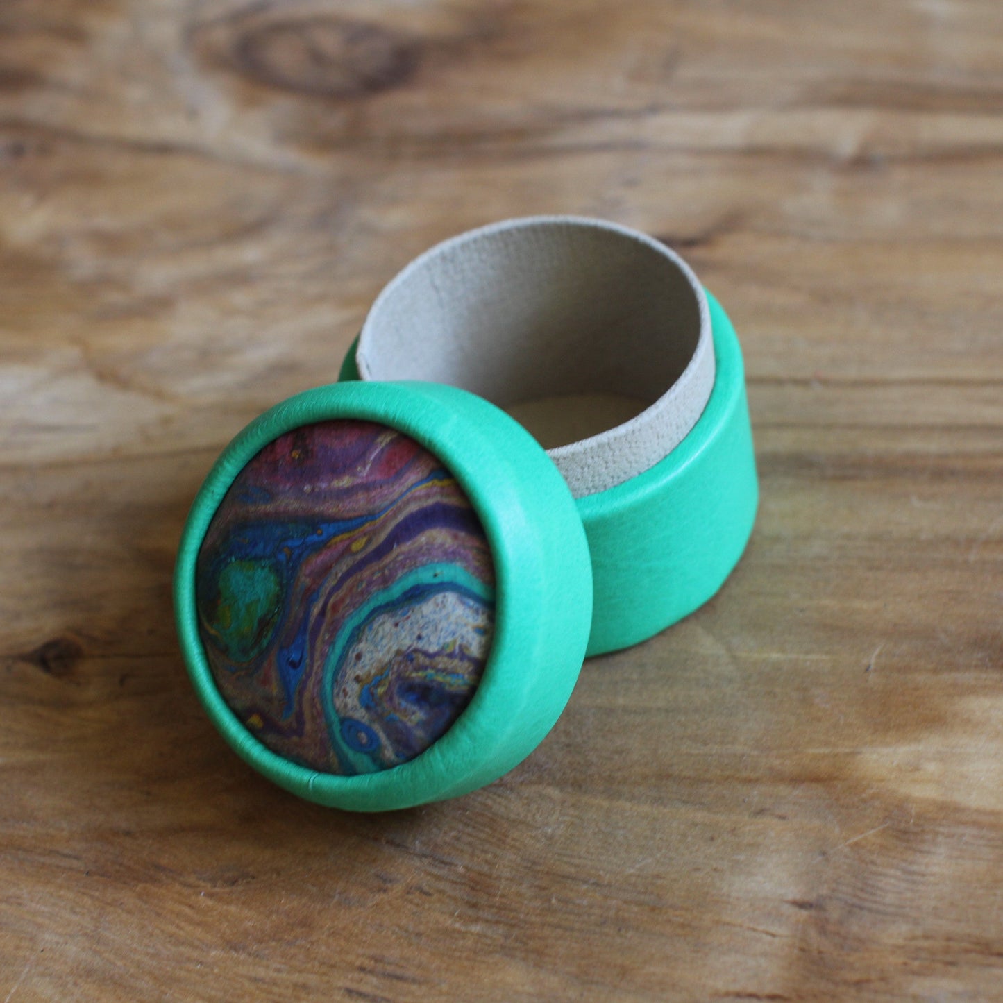 Zilganzaļa, apaļa dekoratīva ādas kārbiņa (S) ar zilgani marmorētu vāku (RARA 253)