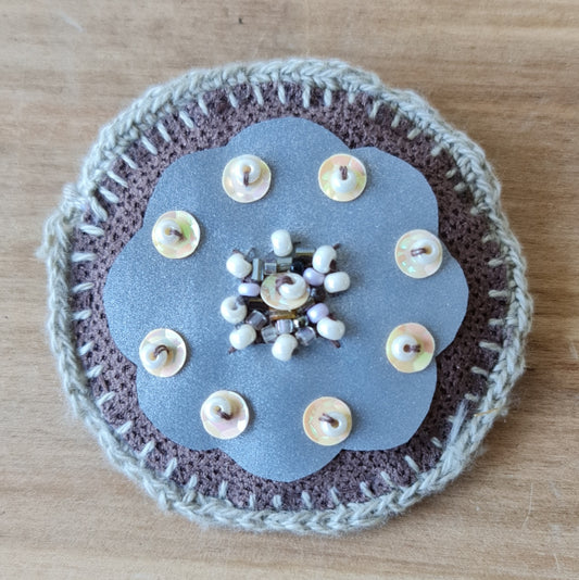 Sewn round brooch with pearl accents in gray-brown tones and reflective fabric at the base / diameter 6.5 cm (AMA)