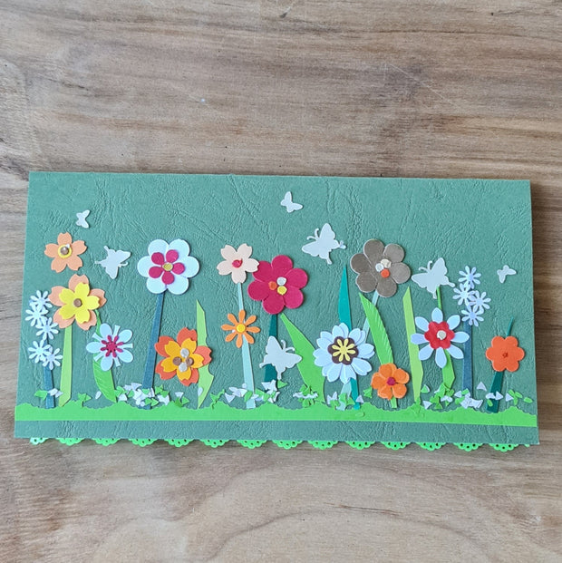 Papīra kartiņa 3D uz zaļa fona ar krāsainu ziedu un tauriņu dekorācijām un mežģīnes veida maliņu / horizontālā 21 x 10.5 cm (AMA)