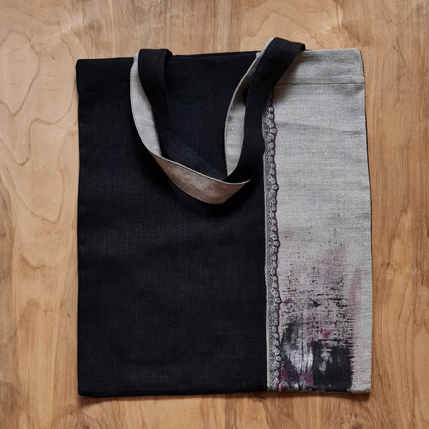 Nekrāsota un melna lina auduma iepirkumu maisiņš/soma ar vertikālu 2 joslu audumu maiņu / mežģīnes veida vertikālu joslu / melni rozā toņu krāsu dekoru apakšājā daļā un uz pleca liekamiem rokturiem (ZMI)