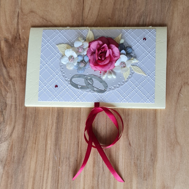 Dāvanu aploksne kremkrāsā kāzām. Ar 3D rozā un baltiem ziediem un sudraba krāsas gredzeniem un sarkanīgas lentas aizdari 11 x 18 cm (APU2)