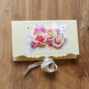 Dāvanu aploksne kremkrāsā ar 3D rozīgi baltiem ziediem un kremkrāsas lentas aizdari 11 x 18 cm (APU2)