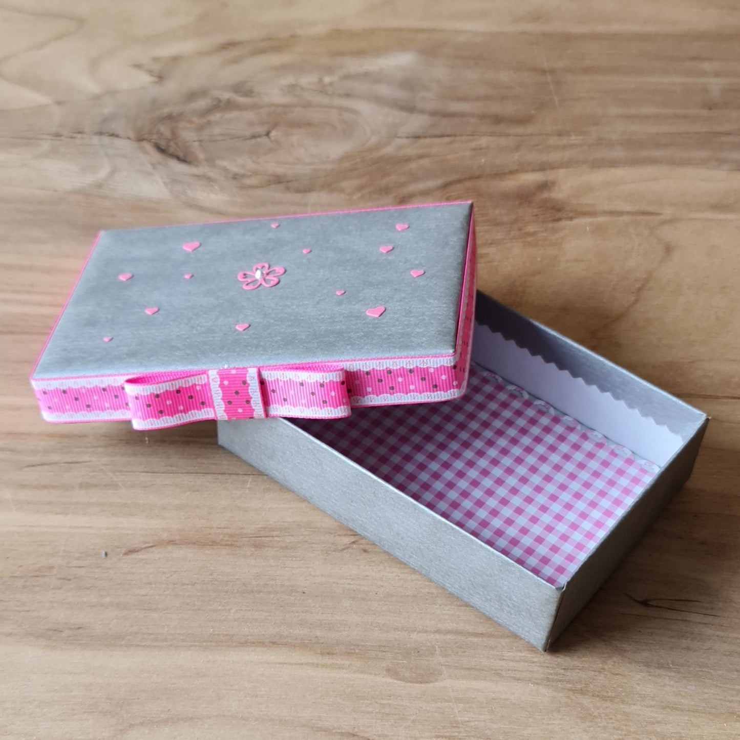 Gift box (inner dimensions 11.8 x 7.8 cm) in silver color with pink ribbon around the edge of the lid and pink/white checkered interior (APU2)