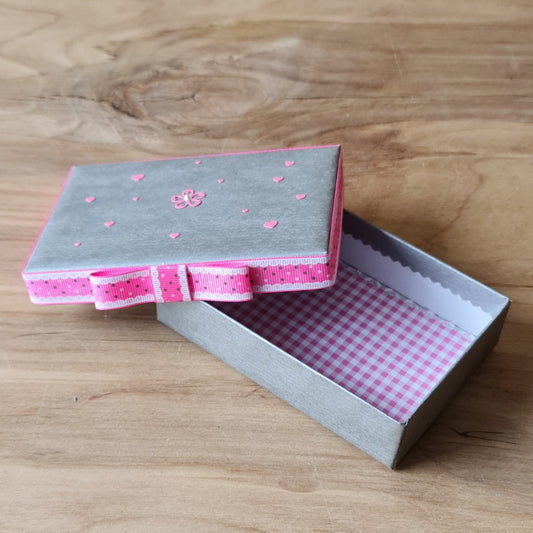Dāvanu kārbiņa (iekšējie izmēri 11.8 x 7.8 cm) sudrabainā krāsā ar rozā joslas lentu ap vāka malu un rozā/balti rūtotu iekšpusi (APU2)
