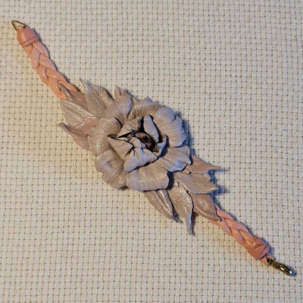 Maigi rozā toņu ādas rokassprādze zieda formā (platums 5.5 cm) ar pītu siksniņu un āķīša veida aizdari (JŠČ)