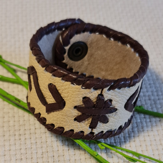 Band-shaped leather bracelet in cream color with dark brown stitched decorative elements and push-button closure (JŠČ)