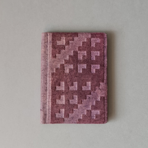 Rūtiņu bloknots ādas ievākojumā. Violetā krāsā ar dekoratīvu iespiedumu. 8 x 10.5 x 1 cm (MAPL 2)