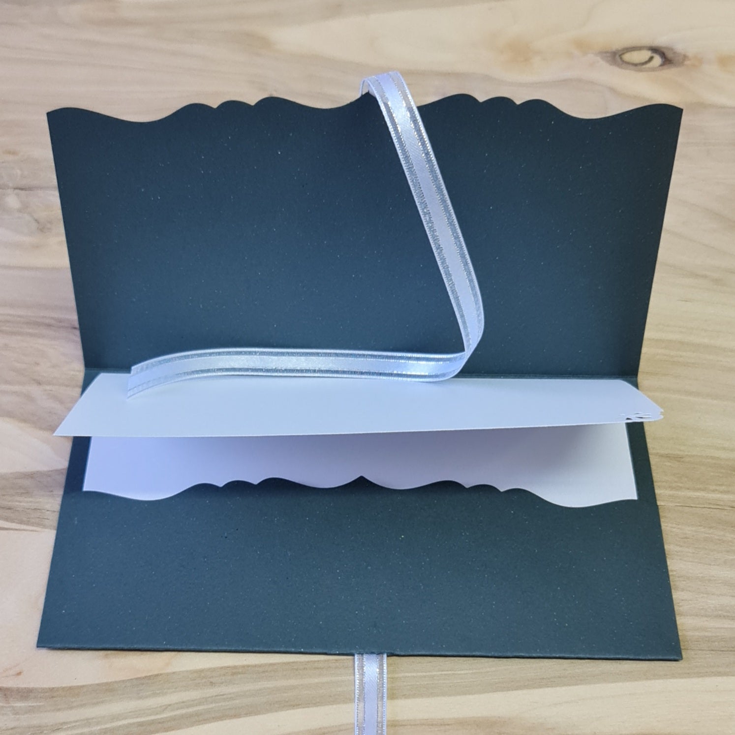 Dāvanu aploksne/kartiņa pelēkzaļganā krāsā ar 3D baltiem un sarkaniem ziediem uz gaiša fona / balti sudrabotas lentītes aizdare / iekšpusē balta vēlējuma daļa 10.8 x 18 cm (AIPU) - www.tiptip.lv 