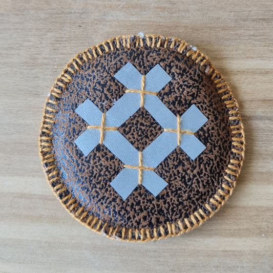 Šūts apaļš dekors ar atstarojošu akas zīmi vienā pusē un saules zīmi otrā un mīkstu brūnu pamatni / diametrs 7.5 cm (AMA) - www.tiptip.lv 