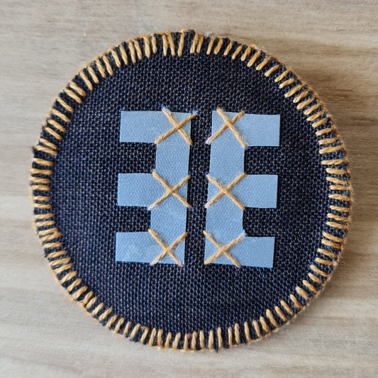 Šūts apaļš dekors ar atstarojošu Ūsiņa zīmi vienā pusē un Austras koku otrā un mīkstu tumši brūnu pamatni / diametrs 7.5 cm (AMA) - www.tiptip.lv 